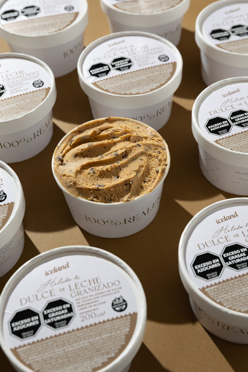 Pote abierto de helado de Dulce de Leche Granizado sin gluten, rodeado de potes cerrados